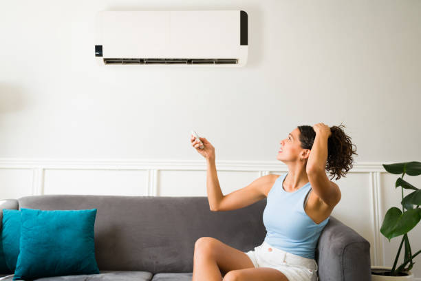 mujer con calor intentando encender aire acondicionado averiado en casa Barcelona