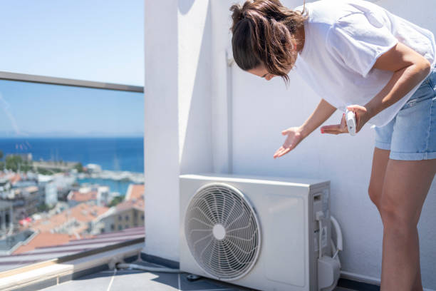 mujer revisando unidad exterior de aire acondicionado en terraza de Barcelona