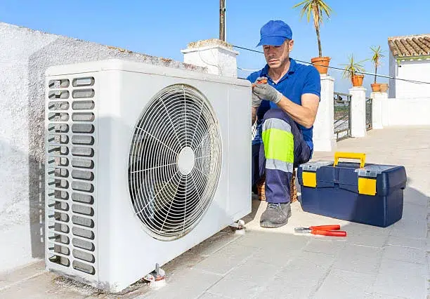 tecnico revisando unidad exterior de aire acondicionado en terraza durante mantenimiento anual